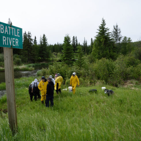 A class stand down at the river on their field trip. A Battle River Sign is in the foreground